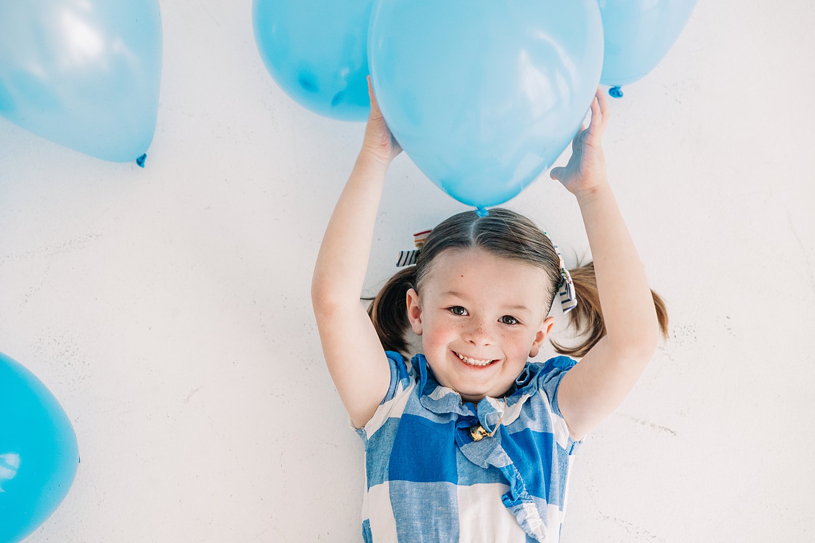 girl in blue birthday dress with blue balloons